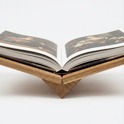 Wooden book stand holding an open book on a white background