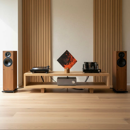 Home theater setup with speakers and a console in a room with wooden flooring and walls.
