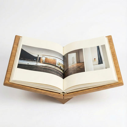 Open book with interior design images on a wooden stand against a white background