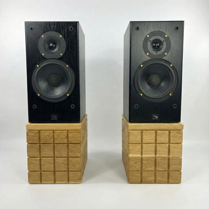 Pair of black speakers on wooden stands against a white background