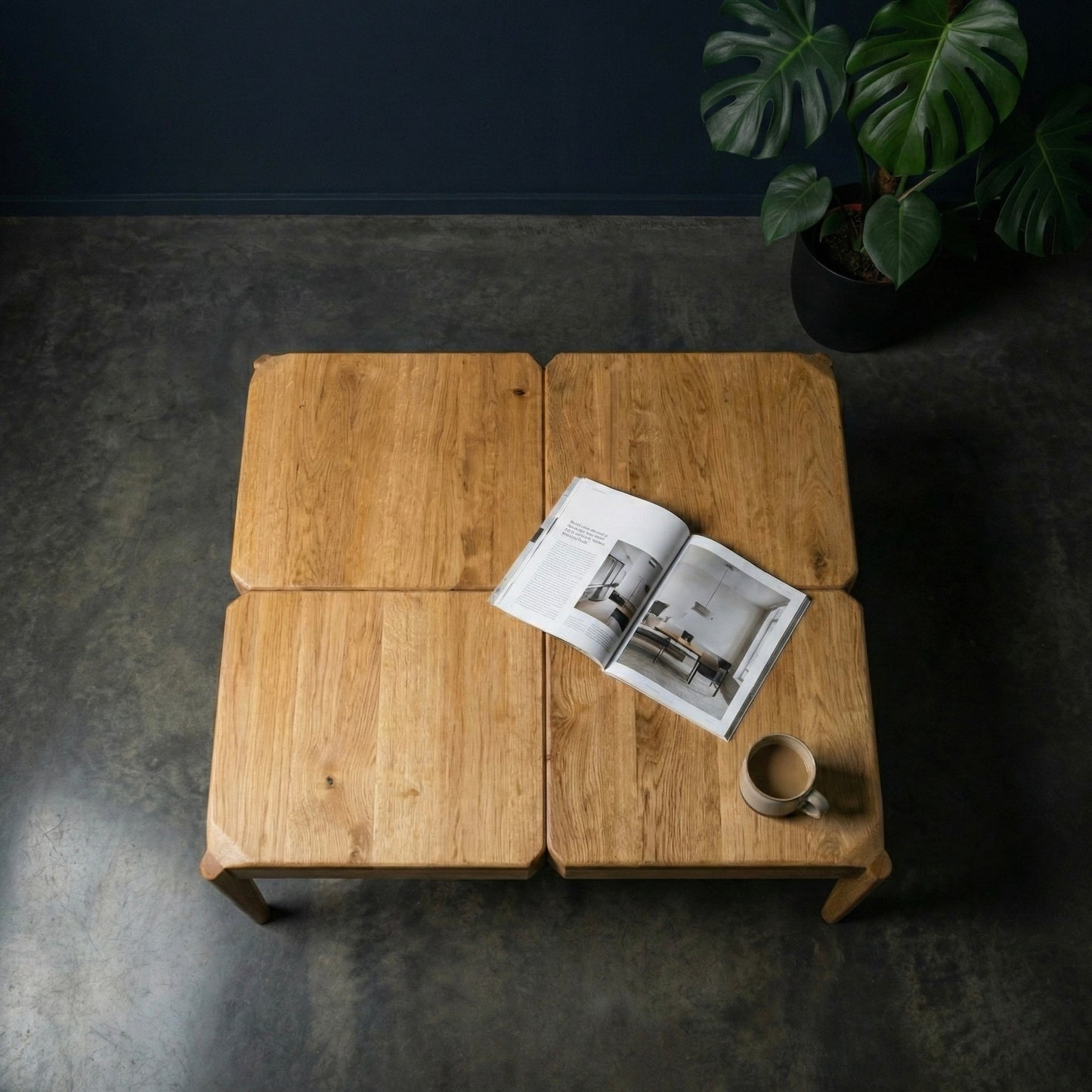 Wooden coffee table with an open magazine and a cup on a dark floor.