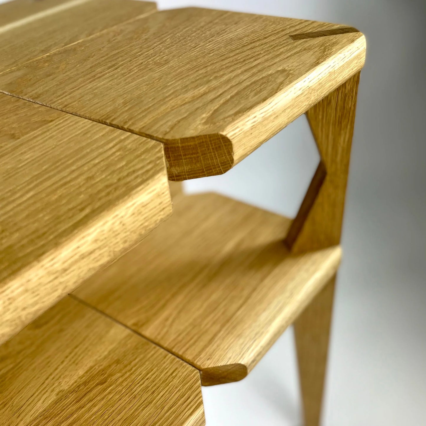 Wooden stool with a light brown finish on a white background