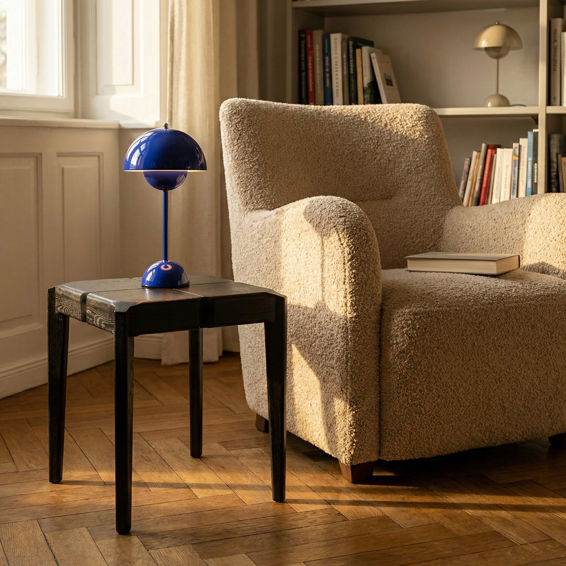 A wooden side table in a cozy living room with a textured armchair, side table, and blue lamp.